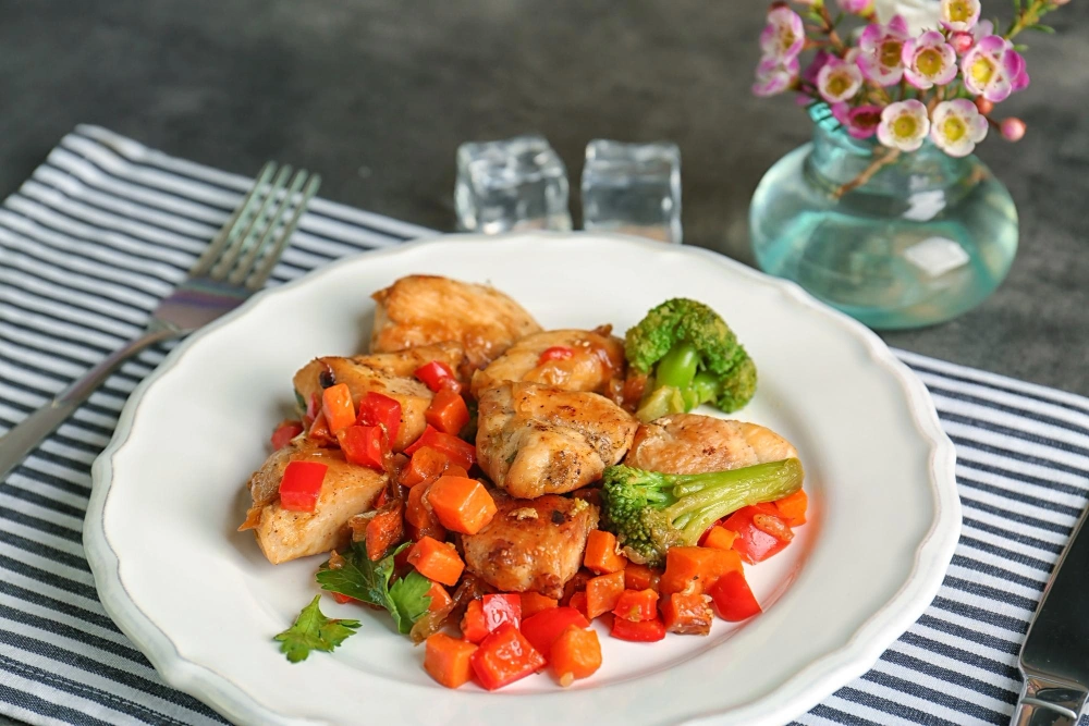 Air fryer honey garlic chicken served on a plate with vegetables.