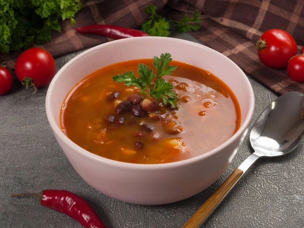 A steaming bowl of Bermuda red bean soup garnished ,showcasing its rich color and hearty ingredients.