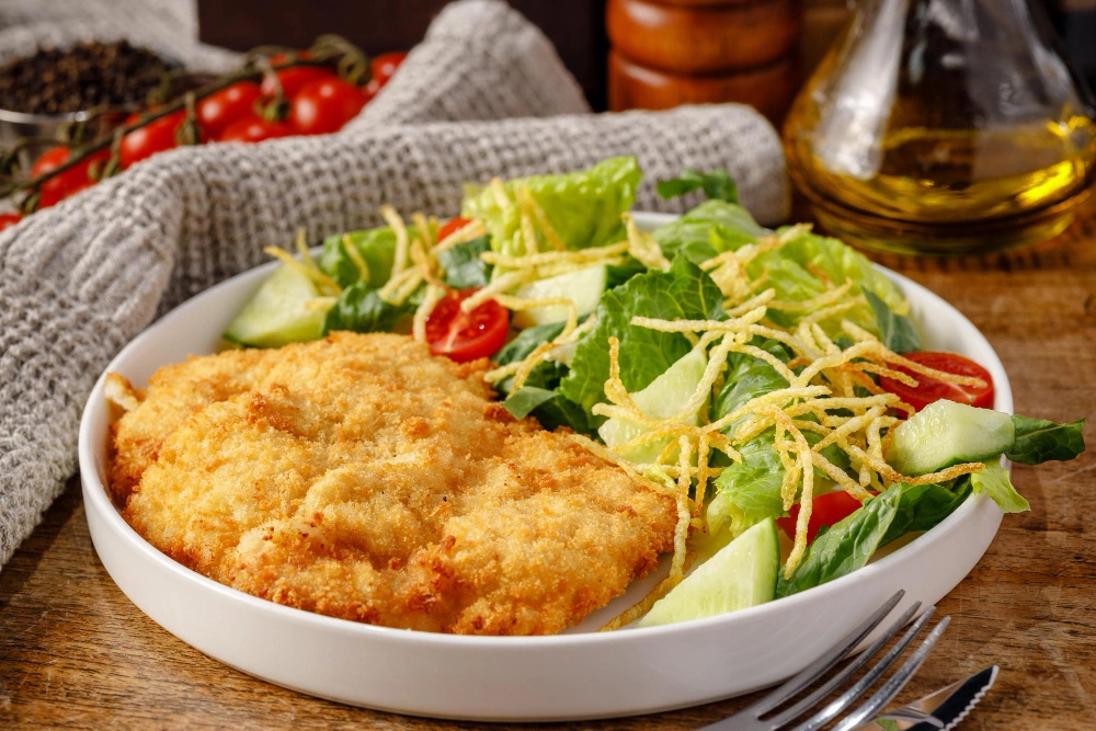 Serving of chicken bubble biscuit bake on a plate with a side salad