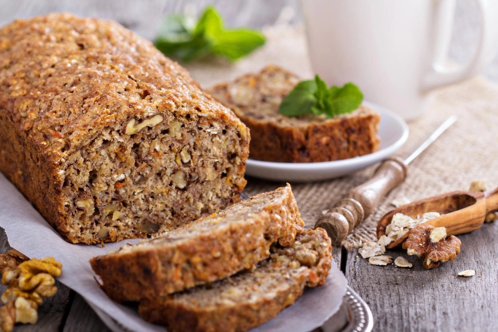 A freshly baked coffee cake with oatmeal streusel topping, served on a rustic wooden table, accompanied by a steaming cup of coffee. The cake is golden brown, with a crunchy, crumbly topping, showcasing its delicious texture and inviting appearance