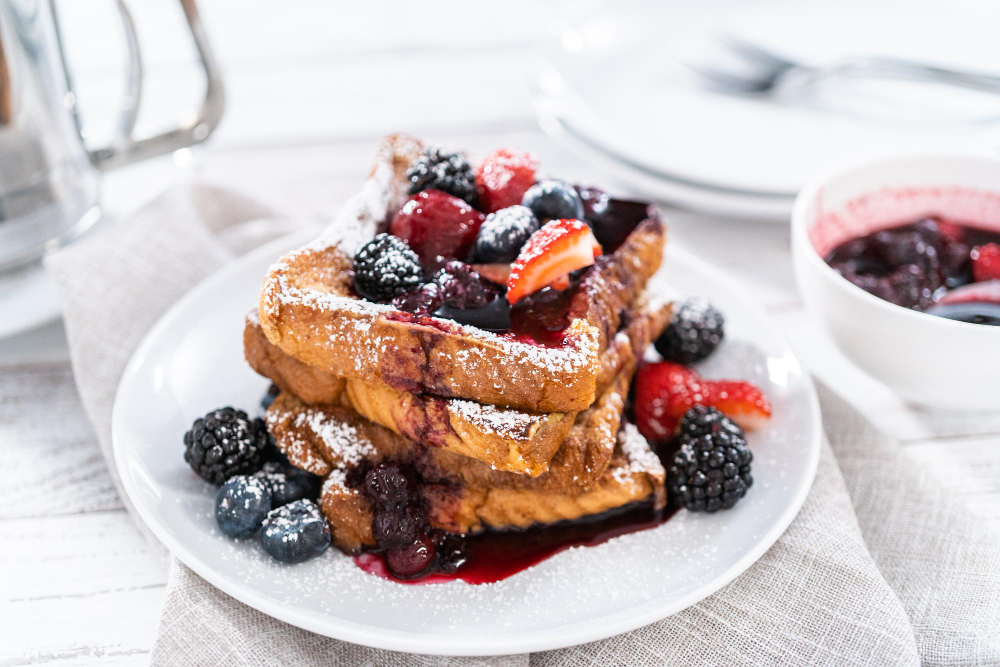 A stack of golden-brown French toast pancakes topped with fresh berries.