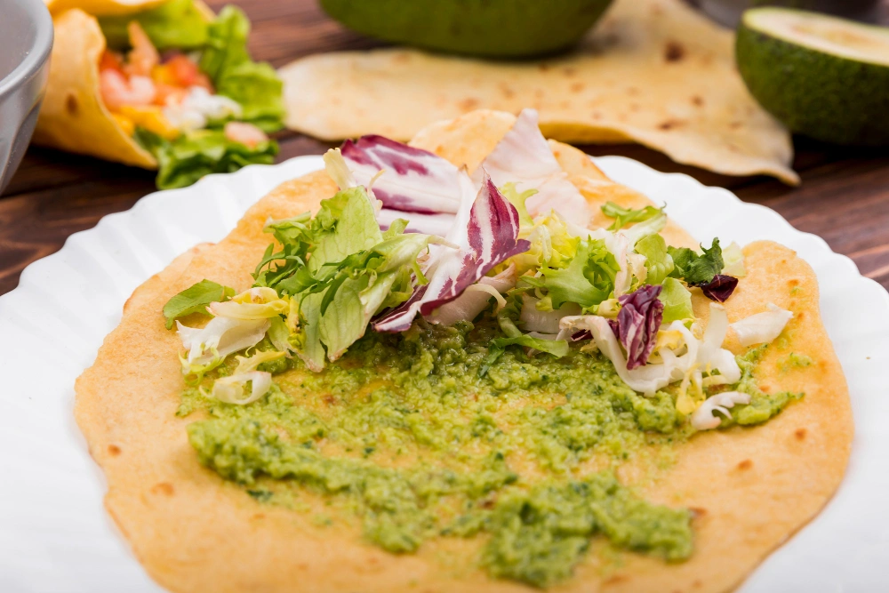 Make Your Own Green Taco Sauce for Flavorful Dishes 3 A close-up of soft tacos filled with meat and topped with vibrant green sauce