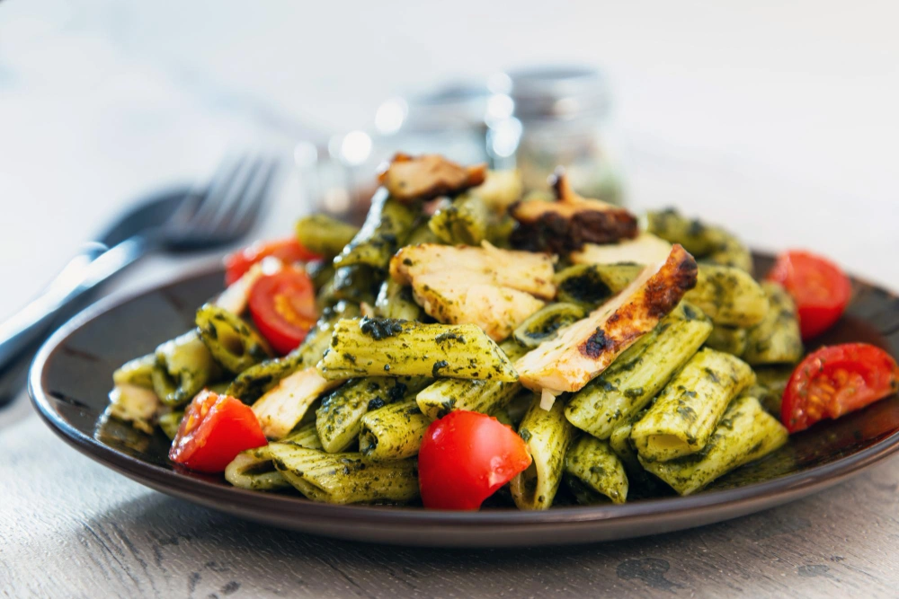 A bowl of pasta salad with chicken and broccoli, garnished with cherry tomatoes and a creamy dressing A colorful.