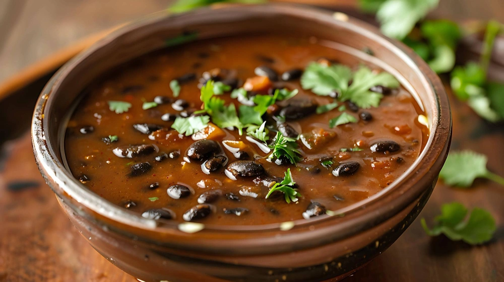 A vibrant bowl of purple black bean soup garnished with fresh herbs , showcasing its rich color and inviting texture, perfect for a nutritious and comforting meal.