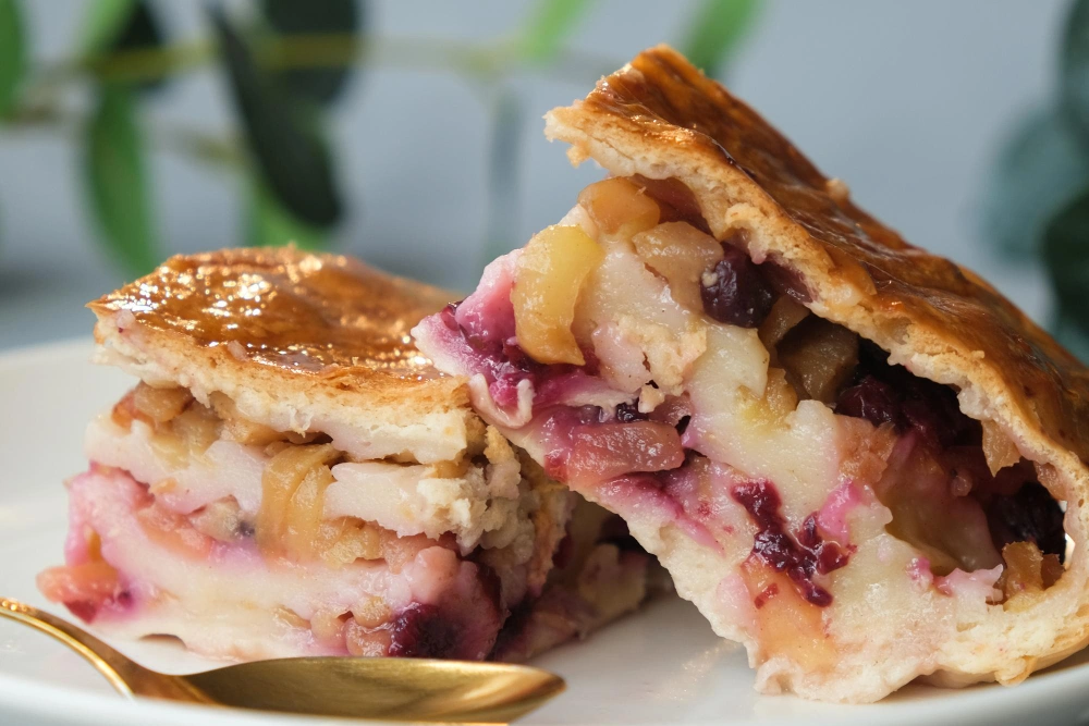 A freshly baked strawberry apple pie served on a plate , showcasing a golden-brown crust and vibrant red strawberries and green apple slices .