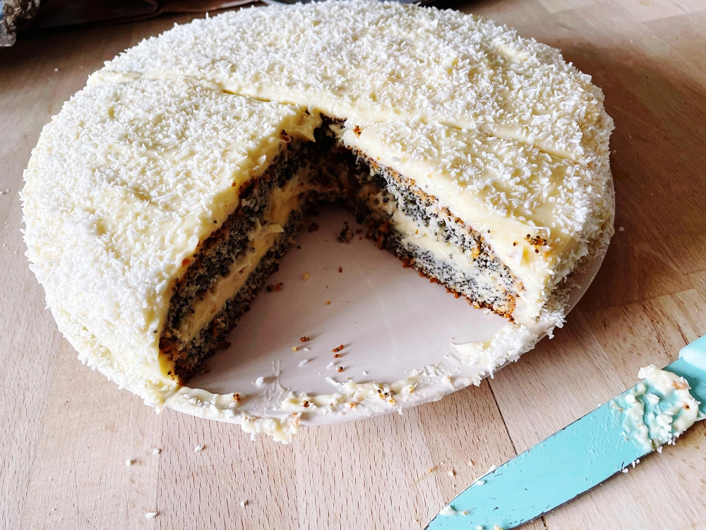 A beautifully decorated vanilla bean cake with a slice cut out, showcasing its moist texture.