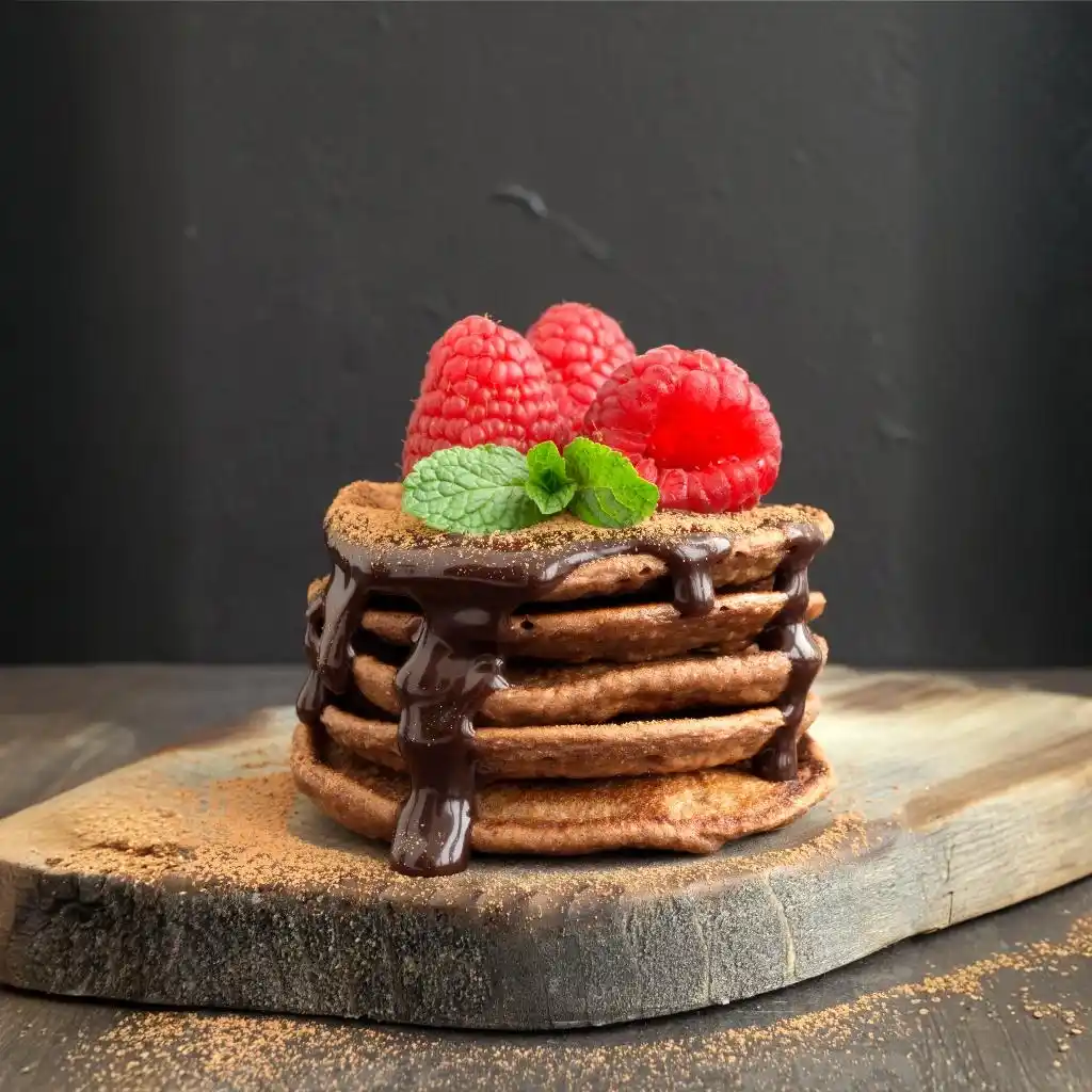 Protein Pancakes Without Protein Powder: Delicious and Nutritious Alternatives 3 Chocolate pancakes with raspberry on a dark background.