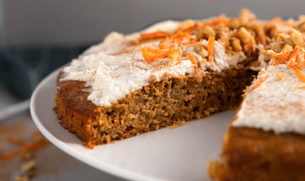 Sliced carrot cake topped with cream cheese frosting, showcasing the delicious flavors of carrot cake with pineapple and coconut.