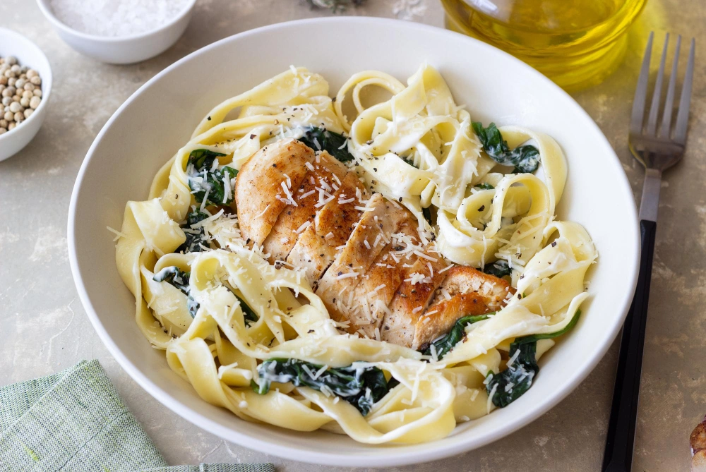 A delicious plate of chicken pasta with boursin cheese, garnished with fresh herbs, showcasing a creamy sauce and tender chicken pieces.