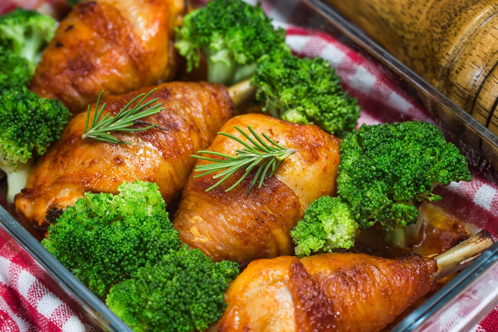 Baking tray with chicken thighs and broccoli roasting in the oven, looking golden and crisp.