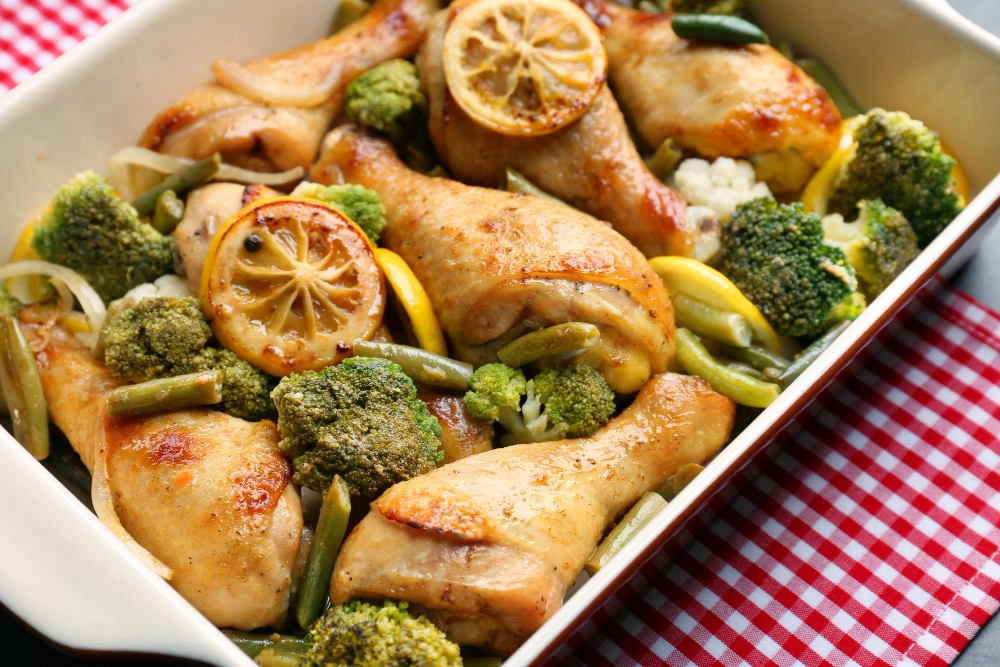 Juicy baked chicken thighs garnished with herbs served on a plate with broccoli florets.