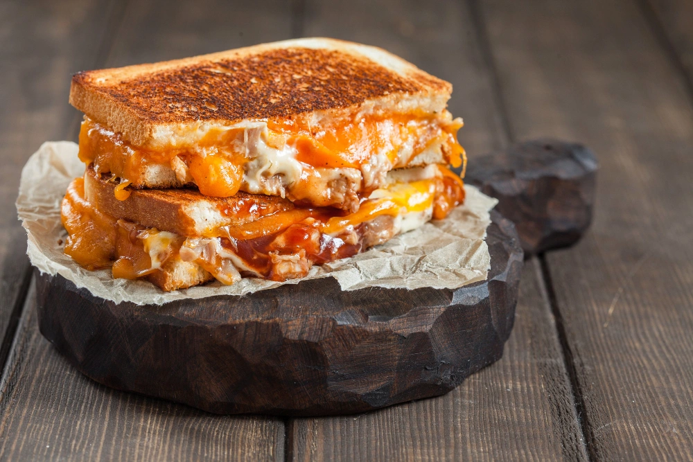 A Hot Honey Chicken Sandwich being held up, showcasing its delicious layers of chicken, honey drizzle, and crunchy toppings.