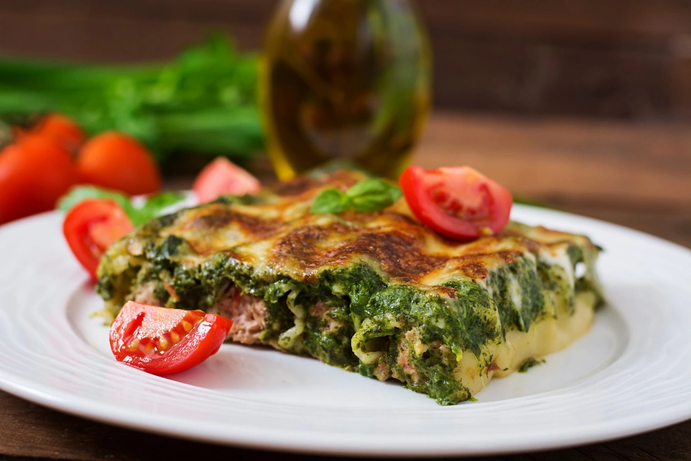 A close-up of lasagnes brocolis ricotta being served on a plate, highlighting the creamy texture and colorful layers.