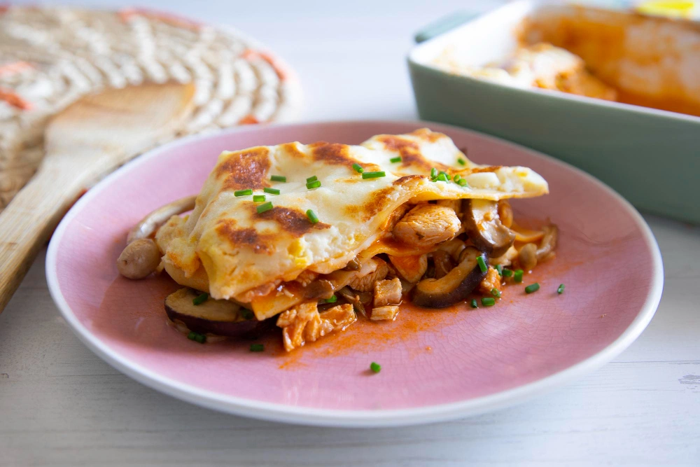 Layered spinach chicken mushroom lasagna with melted cheese on top.