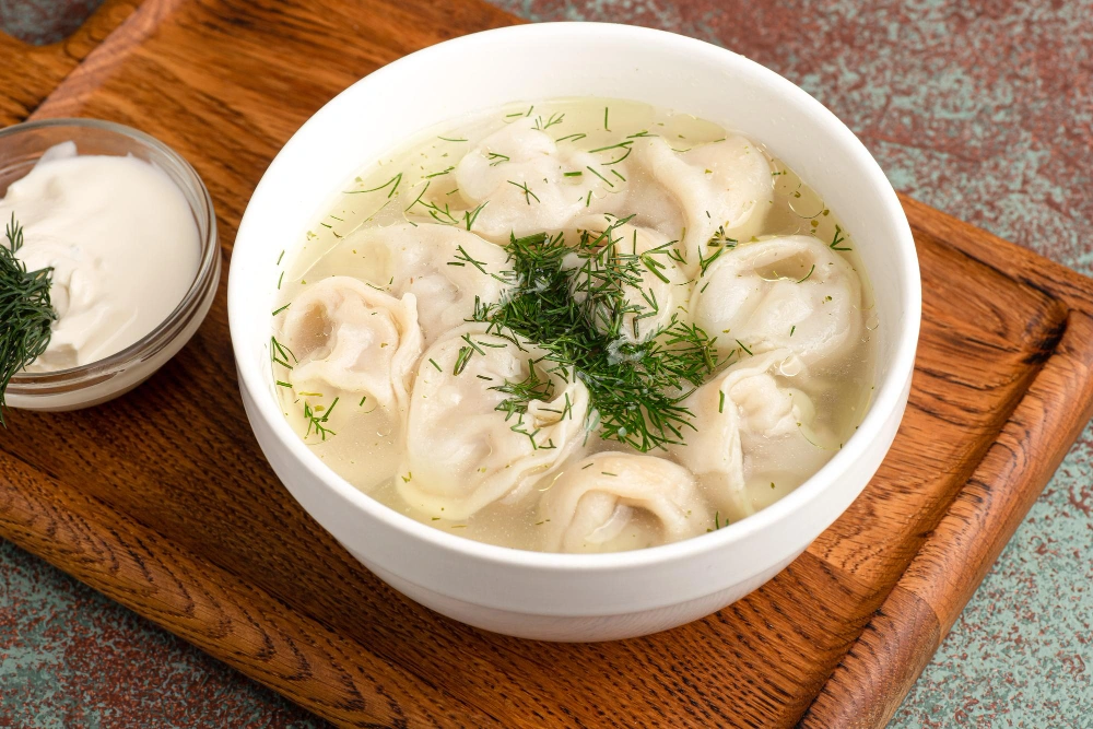 A close-up of vegan soup dumplings, showcasing their delicate, translucent wrappers filled with a savory plant-based mixture, served with a side of dipping sauce.